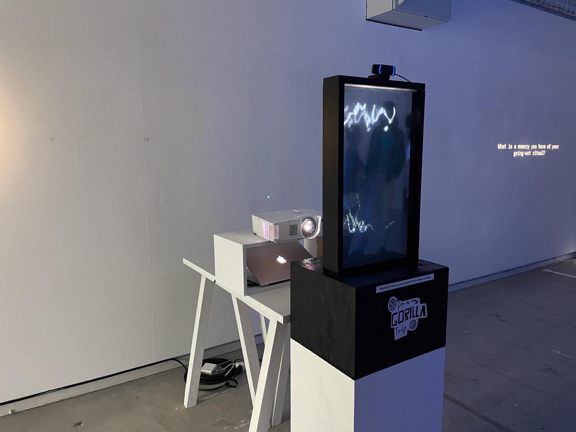 Mirrorilla — side view of the setup with the display, projector and the «going-out ritual» wall text